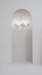 Model sitting in beige embroidered outfit with chandelier and wall sconce lighting